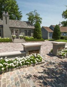 a large brick house with white flowers in the front yard and steps leading up to it