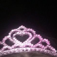 a woman wearing a tiara with pink lights on it's head in the dark