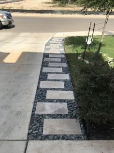 a walkway made out of stones and gravel next to a car parked on the street