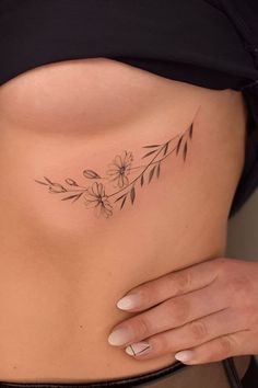 a woman's stomach with a flower tattoo on her left side ribcage