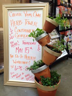 a sign that has some plants in it on the ground next to a pile of potted plants