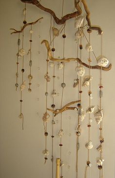 a wall hanging made out of shells and branches with beads attached to the branch,