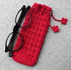 a red crocheted pouch with eyeglasses on it and a pair of black glasses