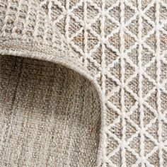 close up view of the textured fabric on top of an area rug that is white and beige