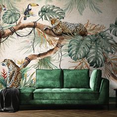 a green couch sitting in front of a wall with leopards and plants on it