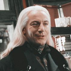 a man with long white hair wearing a black coat