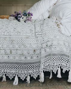 a white crocheted bedspread with tassels and flowers on it