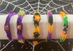 four different colored bracelets on top of a white tube with spider web in the background