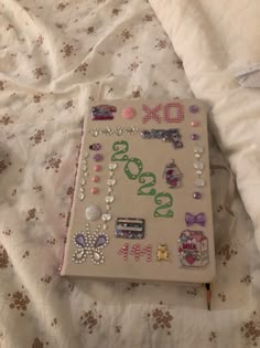 a book covered in lots of different things on top of a white bed sheet with flowers