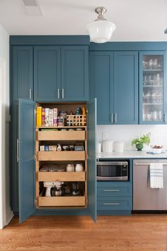 a kitchen with blue cupboards and wooden flooring is pictured in this image, there are