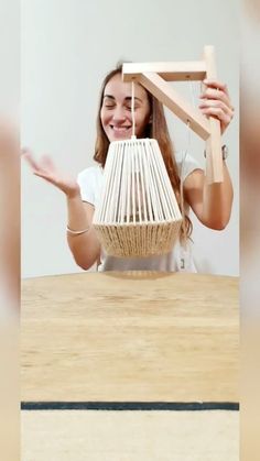 a woman sitting at a table with a basket on her head and hands in the air