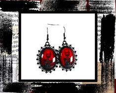 a pair of red earrings sitting on top of a white and black background with an abstract design