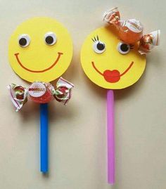 two lollipops with faces on them sitting next to each other in front of a wall