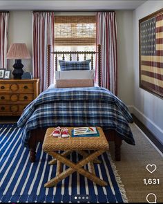 a bed room with a neatly made bed and a blue rug on the floor next to a window