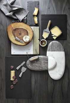 a table topped with plates and cheeses on top of a wooden table next to utensils