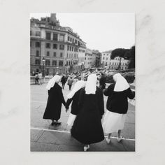 black and white photograph of three women in nun dresses walking down the street holding hands