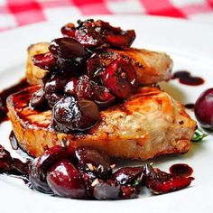 a white plate topped with meat covered in cherries