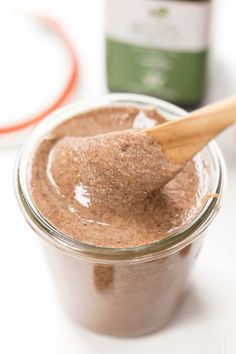 a spoon in a jar filled with brown liquid and cinnamon on the table next to it