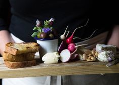 a person holding a tray with bread, vegetables and other foods on it in their hands