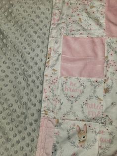 a pink and gray blanket with an animal on it's side next to a polka dot sheet