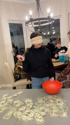 a woman with blindfolded head standing in front of a table full of money