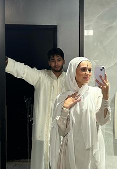 a man and woman taking a selfie in front of a mirror