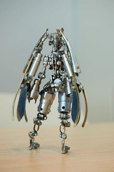 a metal robot standing on top of a wooden table