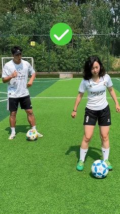 two people are playing soccer on a field with green grass and trees in the background