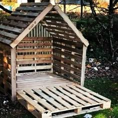 a bed made out of wooden pallets in the grass with a dog house on top