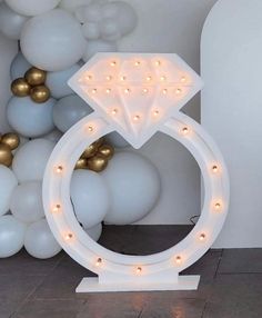 a large white ring with lights on it in front of balloons and wall decorations that look like diamonds