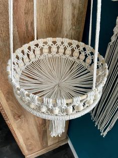 a white macrame hanging from a wooden wall next to a blue and white door