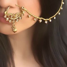 a close up of a woman's face wearing an earring and nose ring