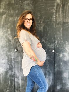 a pregnant woman standing in front of a chalkboard wall with her hands on her stomach