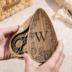 a person holding a wooden box with a pair of scissors in it and the letter w on it