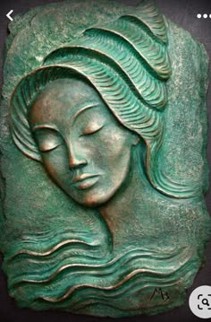 a green ceramic plaque with a woman's face in the shape of a head