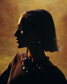 a woman with earrings on her neck looking off into the distance