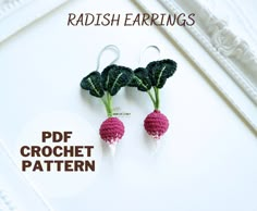 two crocheted radishes hanging from hooks in front of a white frame