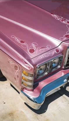 the front end of a pink car with flowers painted on it