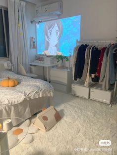 a bed room with a neatly made bed and clothes hanging on the rack in front of a large screen