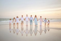 a family standing on the beach holding hands