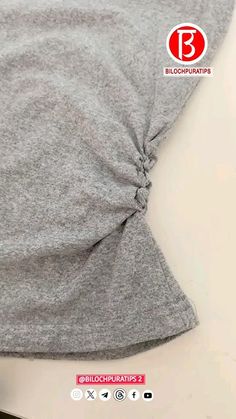 the back side of a gray shirt with a knot on it's front and bottom