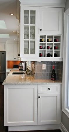 a kitchen with white cabinets and marble counter tops