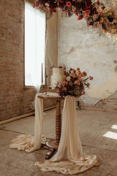 a table with flowers and candles on it next to a brick wall in an old building