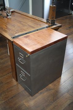 an office desk made out of metal and wood with drawers on each side, sitting on a hard wood floor