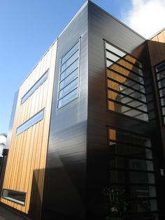 the side of a modern house with wood and metal siding on it's sides