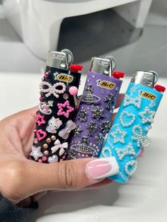 a person holding four lighters in their hand with bows and jewels on the covers