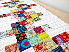 a colorful quilt is laying on the floor in front of a white wall and window