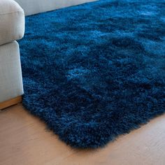 a blue shaggy rug is on the floor in front of a white couch and chair