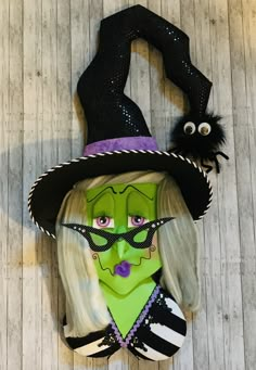 a woman's face is painted green and has a witch hat on top of it