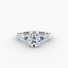 a white gold engagement ring with blue sapphire stones on the side and an oval cut diamond center